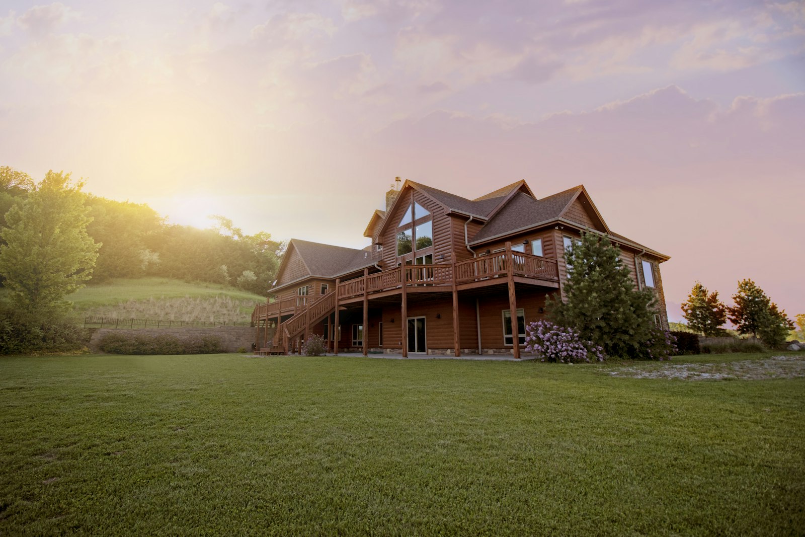 A large multi-level wood deck with railings and stairs on a home at sunset