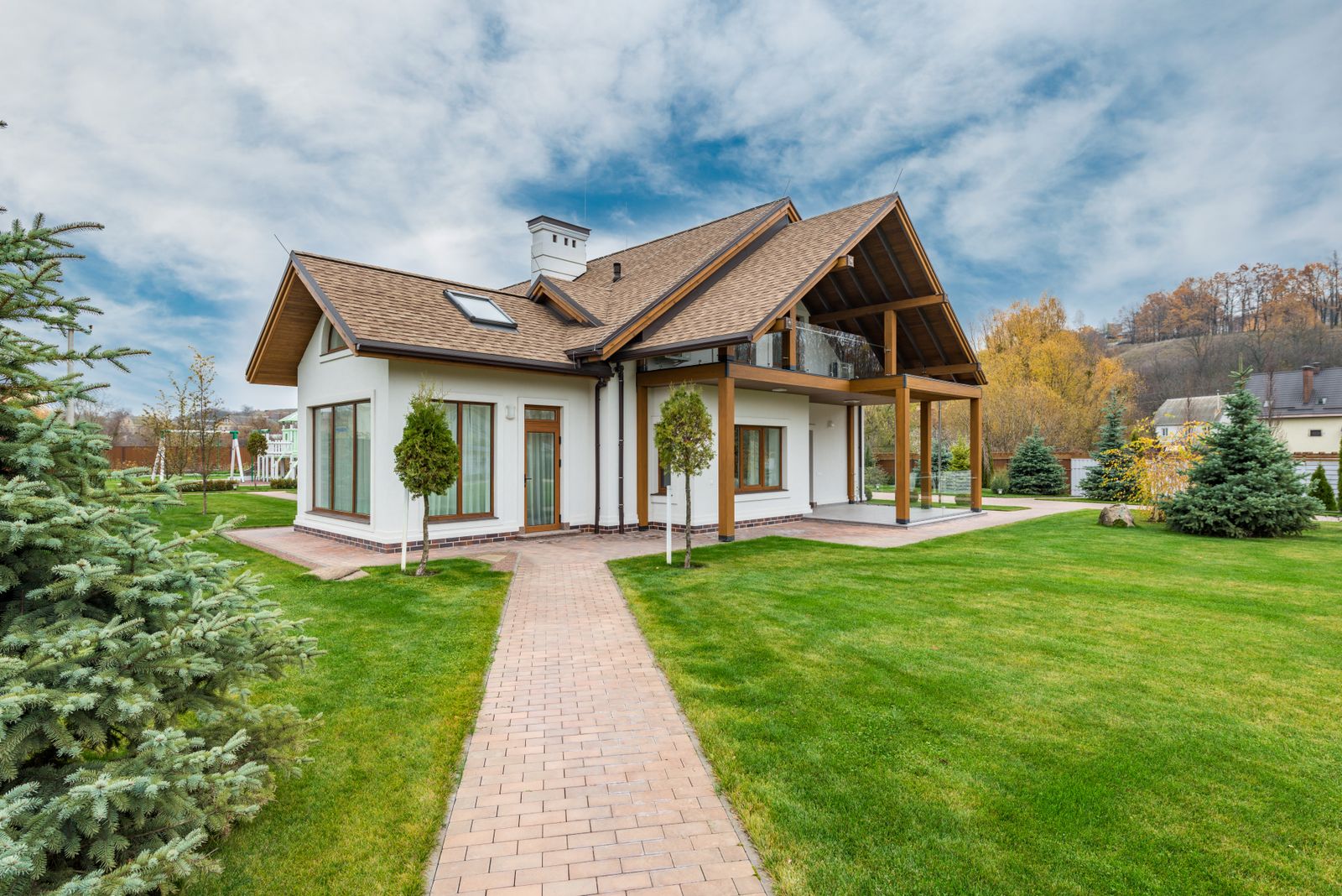 A home with a covered pergola shade structure and a paver patio path through a green lawn